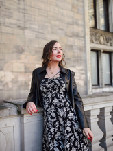 a lady in a camellia printed midi dress with a black leather jacket